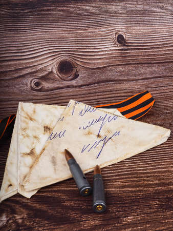 two cartridges, bullet casings on a wooden background, letters about the war the St. George ribbon as a symbol of the Second World War for Victory Day on May 9の写真素材