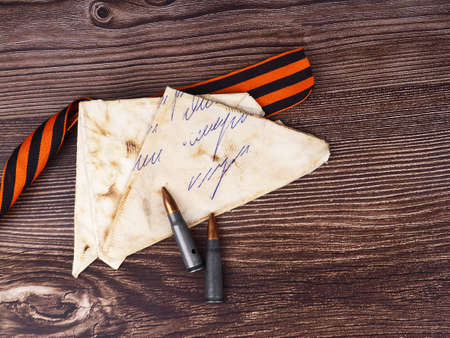 two cartridges, bullet casings on a wooden background, letters about the war the St. George ribbon as a symbol of the Second World War for Victory Day on May 9の写真素材