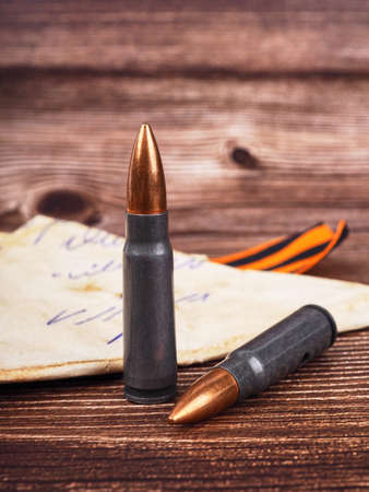 two cartridges, bullet casings on a wooden background, letters about the war the St. George ribbon as a symbol of the Second World War for Victory Day on May 9の写真素材