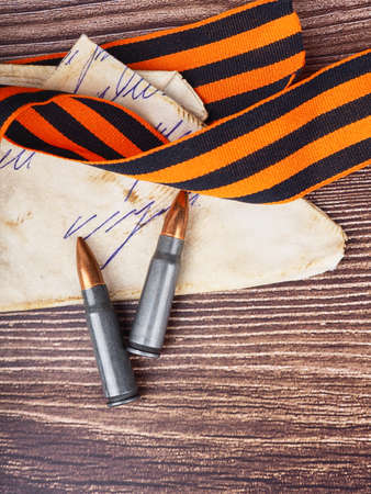 two cartridges, bullet casings on a wooden background, letters about the war the St. George ribbon as a symbol of the Second World War for Victory Day on May 9の写真素材