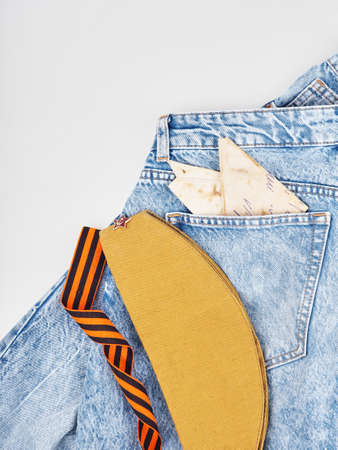 Modern jeans and symbols of victory in the Second World War. St. Georges ribbon, military cap, cartridges and letters from the front. The concept of victory on May 9 for a postcard backgroundの写真素材