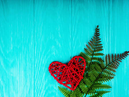 red wicker heart as a symbol of love on a blue wooden background.の写真素材