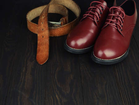 brown men's boots, jeans and belt on wooden background.の写真素材