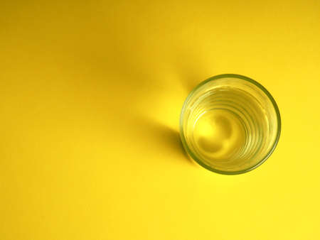 minimalistic concept of water consumption, one glass of water on a yellow background.の写真素材