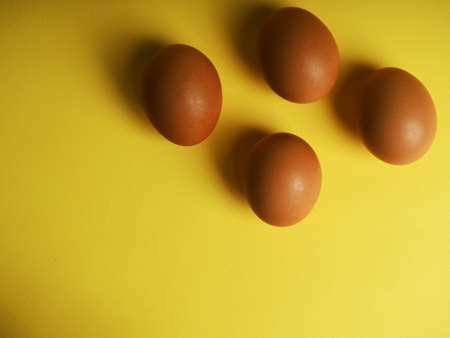 brown eggs on a yellow background with a shadow, modern Easter concept, hidden trend of the year, website banner.の写真素材