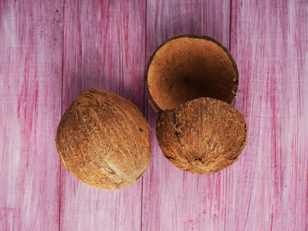 Two coconuts one whole the second is broken on a wooden background.の写真素材