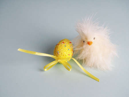 Small white chicken next to colored eggs for Easter.の写真素材