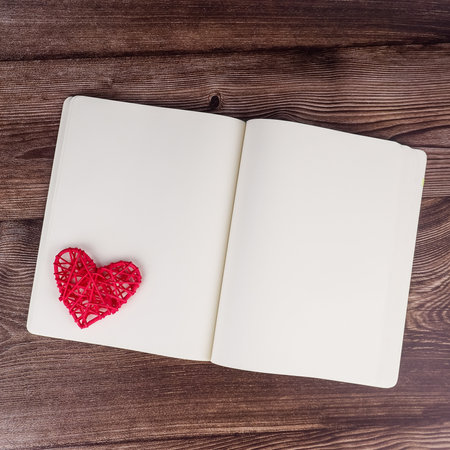 Blank notebook and pen with red heart shape decoration on wooden table background. Wedding, Romantic and Happyの写真素材