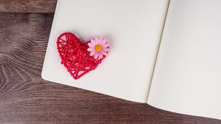 Blank notebook and pen with red heart shape decoration on wooden table background. Wedding, Romantic and Happyの写真素材