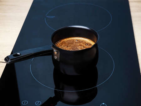 Black turk with coffee on the induction cooker.の写真素材