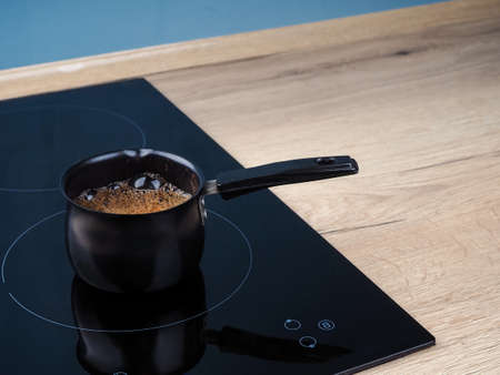 Black turk with coffee on the induction cooker.の写真素材