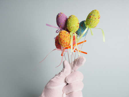 A hand in a white glove holds a bouquet of colored eggs.の写真素材