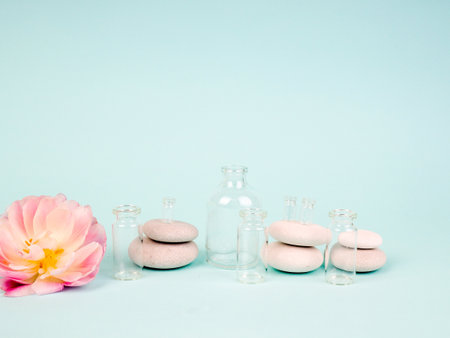 Spa stones, oil bottles and pink flower on white backgroundの写真素材