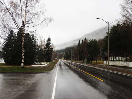 Gloomy landscape with fog on the Norwegian fjords, the road through the village.の写真素材