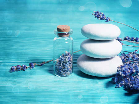 Zen stack stones on a blue wooden background, lavender seeds in a bottle and lavender branches nearby.の写真素材