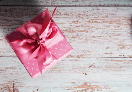 One gift box with a pink bow on a wooden background, copy of the text space.の写真素材