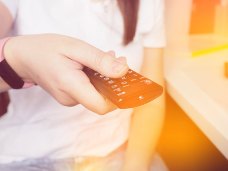 Hands holding the TV remote control, close-up at home.の写真素材