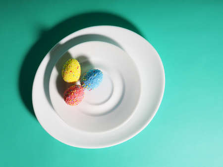 Colorful eggs on a plate, bright green blue background, Easter concept.の写真素材
