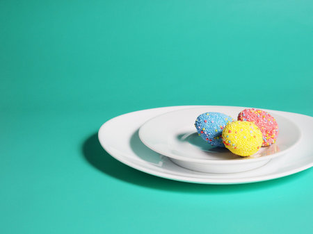 Colorful eggs on a plate, bright green blue background, Easter concept.