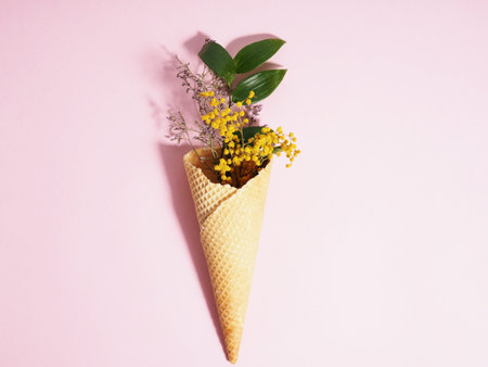 Bouquet of dried flowers in a waffle cup from ice cream, cone, on a pink background, minimalism.