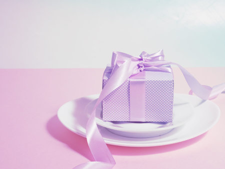 A gift box with a lilac ribbon lies on the plates saucers.