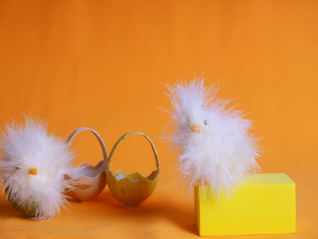 Small white chicken next to colored eggs for Easter on orange.の写真素材