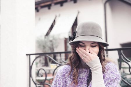 Autumn look for young female: purple wool coat, trousers and a beautiful hat. Capture in a street.の写真素材