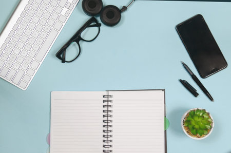 Top view education flat lay with note book, keyboard, glasses, headphones, smartphone, a pen and...