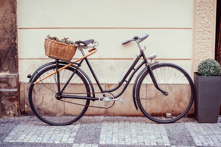 Vintage bicycle with an old basket at the back of it left in the street of Prague's old town.の写真素材