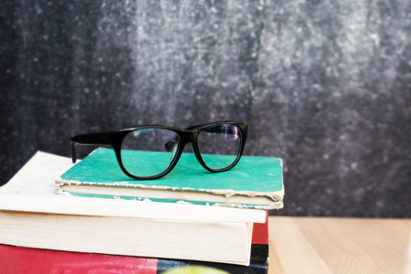 Table with books black chalk board and black glasses. の写真素材