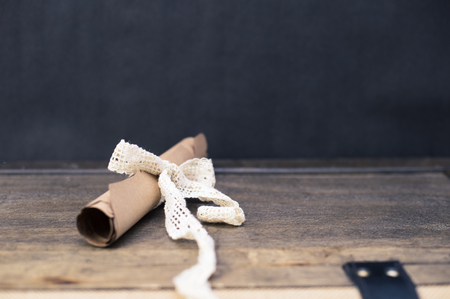 Scrolled brown papyrus with a beautiful ribbon for valentine message with simple black backgroundの写真素材