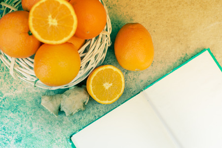 top view composition fresh cut oranges on a kitchen table, piece of ginger and blank pagesの写真素材
