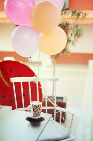 Colorful surprise table in outdoor cafe with balloons and a mug with cappuccino latte in Tirana, Albania, soft pastel tones background の写真素材