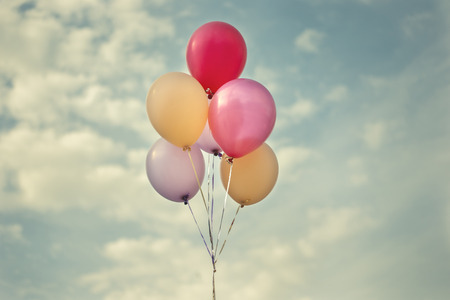 Several colourful balloons pastel colors floating in air, soft toned sky background の写真素材