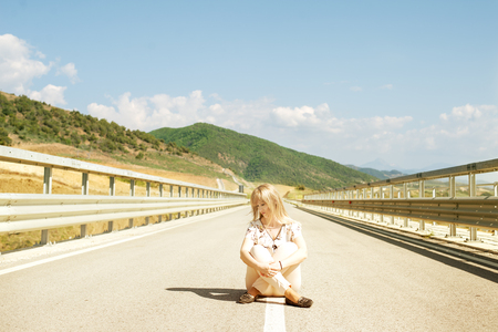 Young woman with closed eyes sitting down on roadの写真素材