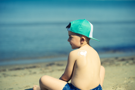 sun protection- little boy with suncream at beachの写真素材