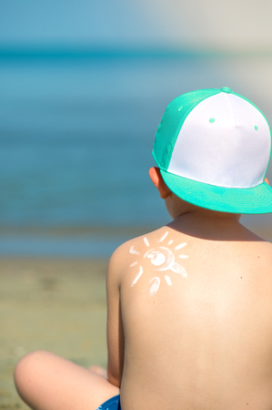 sun protection- little boy with suncream at beachの写真素材