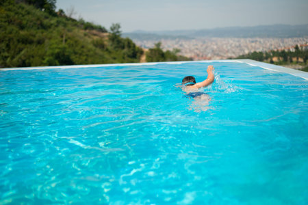 Child swim in the pool at the hotel. View from above.
