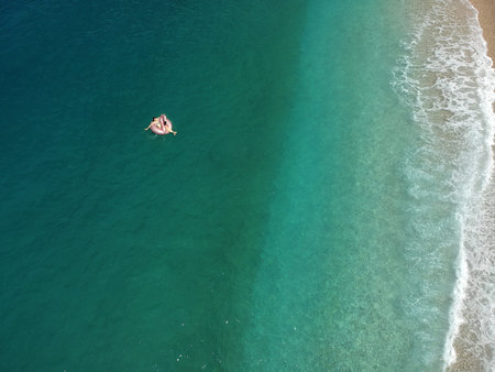 Aerial view young woman on giant inflated flamingo float in turquois water of Ionian Sea Albania