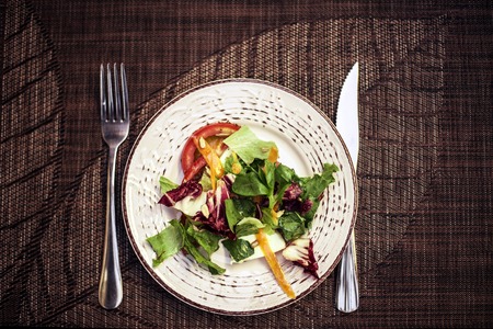 appetizer - salad with tomato and cucumber on white plate top view, dark wood tableの写真素材