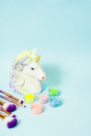 Head of a unicorn and glitter eye shadows on a blue background.の写真素材