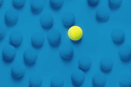Individuality concept with tennis balls top view duotone blue background and one different ballの写真素材