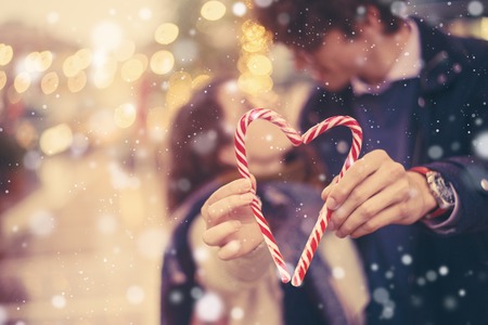 Romantic couple holds a holiday christmas candy cane heartの写真素材