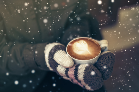 Woman hands in warm wool mittens embracing of hot coffee mugの写真素材