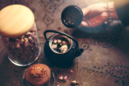 rose tea and flower in the pot with muffin and bokeh