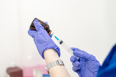 Hand in a blue glove holding syringe isolatedの写真素材