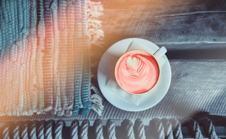 Cup of fresh aroma coral color cappuccino with beautiful latte art heart on wooden backgroundの写真素材