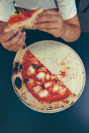 High angle shot of unrecognizable peoples hand grabbing a slice of pizzaの写真素材