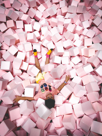 Happy child lying on soft colored cubes in a game room