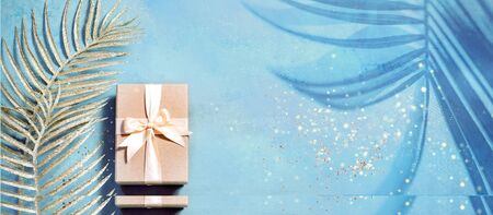 gift box top view on minimal background with Golden festive palm tree leavesの写真素材
